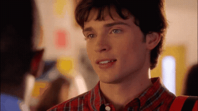 A Young Man In A Plaid Shirt Is Smiling And Looking At Something GIF