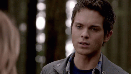 A Young Man In A Plaid Shirt Looks At A Woman In A Forest GIF