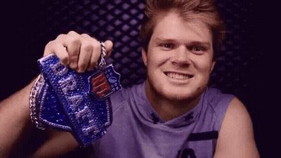 A Young Man In A Purple Shirt Is Holding A Nfl Championship Trophy . GIF