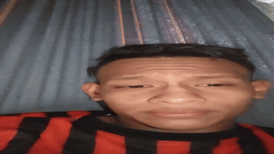 A Young Man In A Red And Black Striped Shirt Is Making A Face GIF
