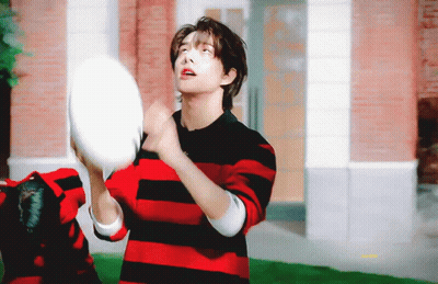 A Young Man In A Red And Black Striped Shirt Is Throwing A Frisbee In The Air . GIF