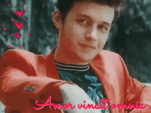 A Young Man In A Red Jacket With The Words Amor Vincit Omnia GIF