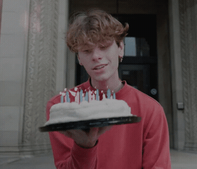 A Young Man In A Red Shirt Holds A Cake With Candles On It GIF