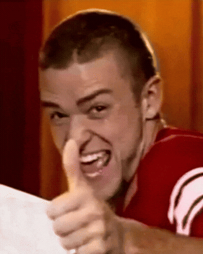 A Young Man In A Red Shirt Is Giving A Thumbs Up Sign . GIF