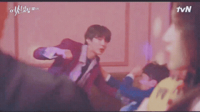 A Young Man In A Red Suit Is Standing In Front Of A Pink Wall And Looking At The Camera . GIF