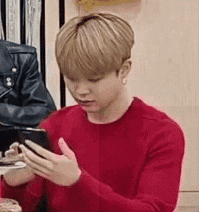 A Young Man In A Red Sweater Is Using A Cell Phone . GIF