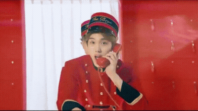 A Young Man In A Red Uniform Is Talking On A Red Phone . GIF
