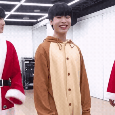 A Young Man In A Reindeer Costume Is Smiling In A Room GIF
