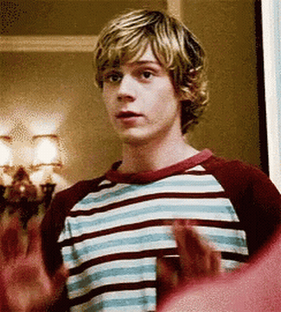 A Young Man In A Striped Shirt Is Standing In A Room With His Hands Outstretched . GIF