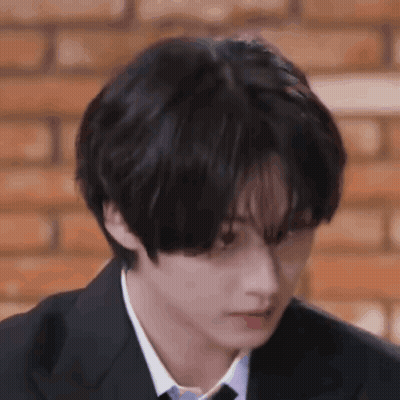 A Young Man In A Suit And Tie Is Looking Down . GIF