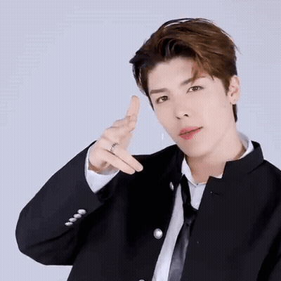 A Young Man In A Suit And Tie Is Making A Peace Sign With His Finger . GIF