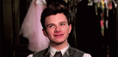 A Young Man In A Suit And Tie Is Smiling And Making A Funny Face . GIF
