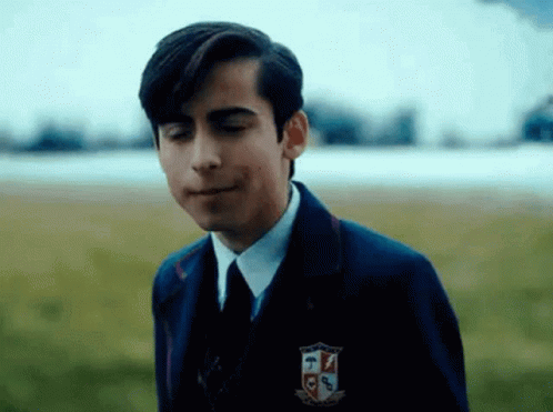A Young Man In A Suit And Tie Is Standing In A Field With His Mouth Open . GIF