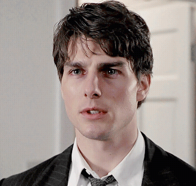A Young Man In A Suit And Tie Looks At The Camera GIF