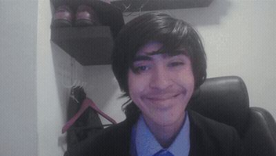 A Young Man In A Suit And Tie Smiles In Front Of A Pair Of Shoes GIF