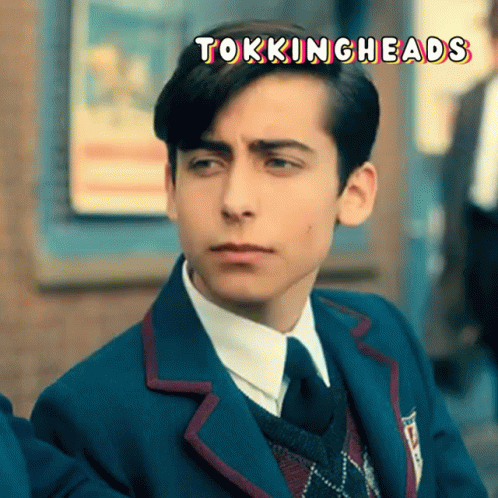 A Young Man In A Suit And Tie With The Words Tokingheads Written Above Him GIF