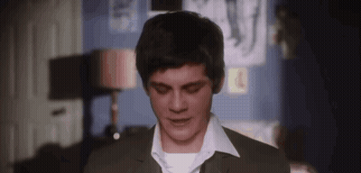 A Young Man In A Suit And White Shirt Is Standing In A Room And Looking Down . GIF