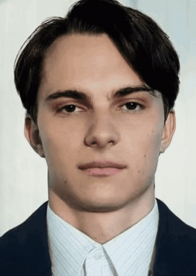 A Young Man In A Suit And White Shirt Looks At The Camera With A Serious Look On His Face GIF