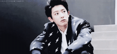 A Young Man In A Suit With Lightning Bolts On It Is Sitting On Stairs . GIF
