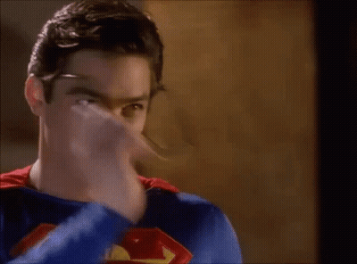 A Young Man In A Superman Costume Is Holding A Pencil In His Mouth . GIF