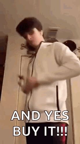 A Young Man In A White Jacket Is Standing In Front Of A Door . GIF