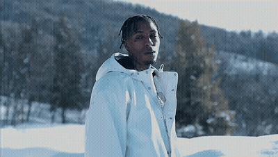 A Young Man In A White Jacket Stands In The Snow GIF
