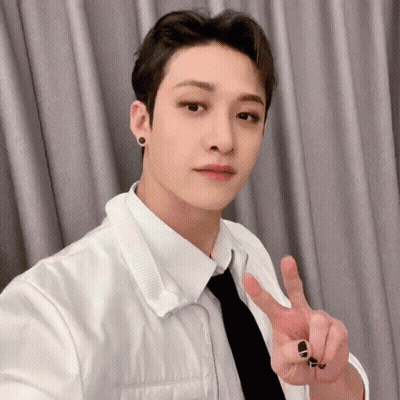 A Young Man In A White Shirt And Tie Is Giving The Peace Sign . GIF