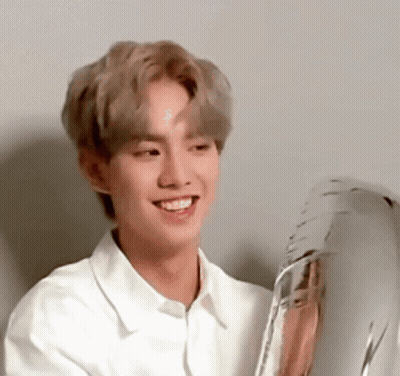 A Young Man In A White Shirt Is Smiling And Holding A Balloon . GIF