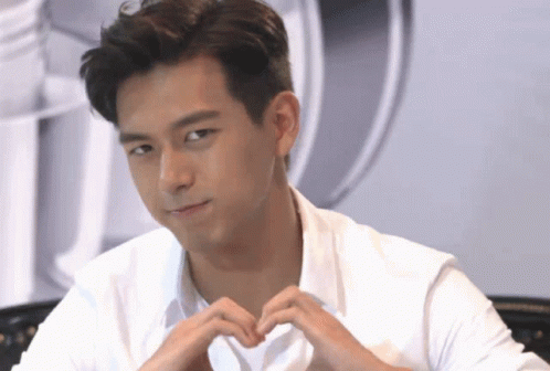 A Young Man In A White Shirt Making A Heart Shape With His Hands GIF