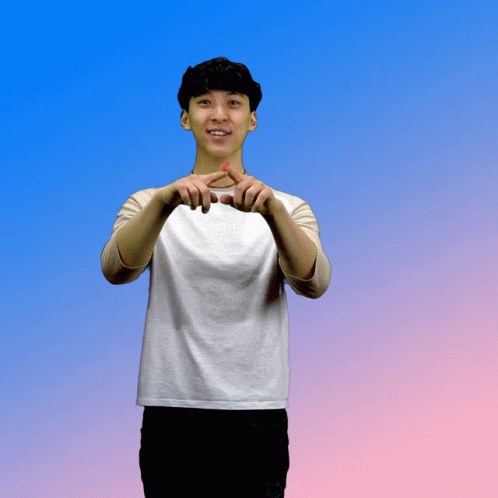A Young Man In A White Shirt Making A Heart Shape With His Hands GIF