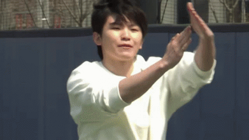 A Young Man In A White Sweater Is Clapping His Hands . GIF