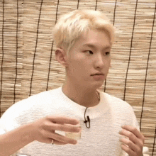 A Young Man In A White Sweater Is Holding A Cup Of Coffee In His Hand . GIF