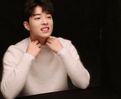 A Young Man In A White Sweater Is Smiling GIF