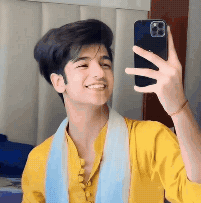 A Young Man In A Yellow Shirt Is Taking A Selfie With His Cell Phone . GIF