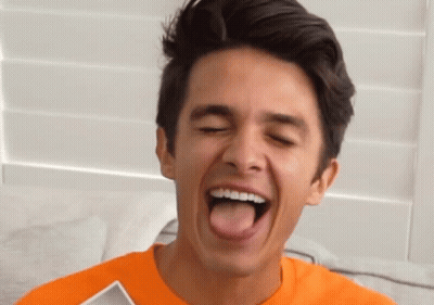 A Young Man In An Orange Shirt Sticks His Tongue Out GIF
