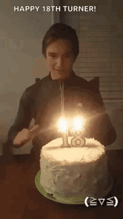 A Young Man Is Blowing Out The Candles On His 18Th Birthday Cake . GIF