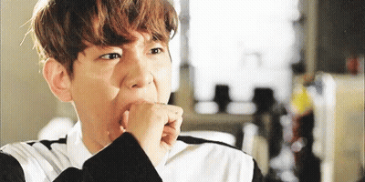 A Young Man Is Covering His Mouth With His Hand While Looking At The Camera . GIF
