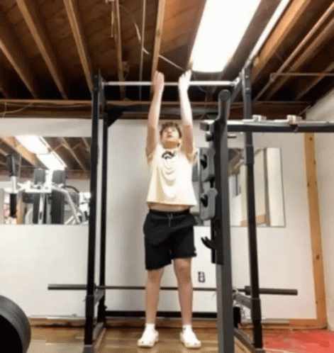 A Young Man Is Doing A Pull Up In A Gym GIF