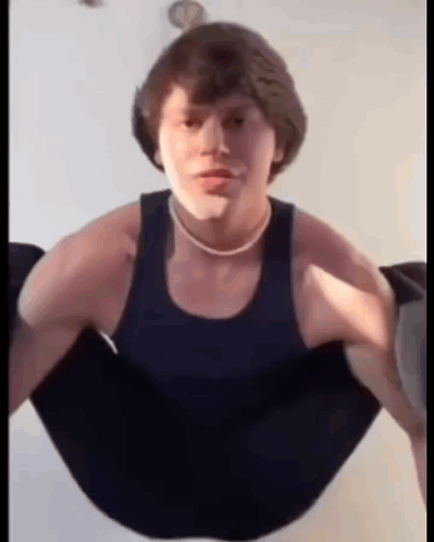 A Young Man Is Doing Push Ups In A Black Tank Top And A Necklace . GIF