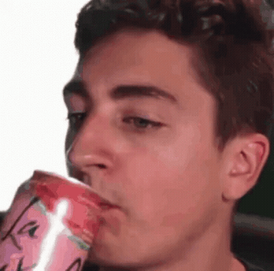 A Young Man Is Drinking A Can Of Soda From A Cup . GIF