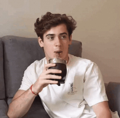 A Young Man Is Drinking From A Cup That Says The Valley Club GIF