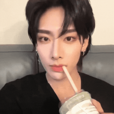 A Young Man Is Drinking From A Cup With A Straw In His Mouth . GIF