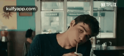 A Young Man Is Drinking Through A Straw In A Restaurant . GIF