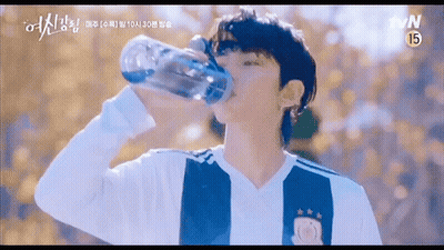 A Young Man Is Drinking Water From A Bottle . GIF