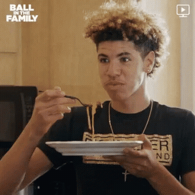 A Young Man Is Eating Spaghetti With A Spoon From A Plate . GIF