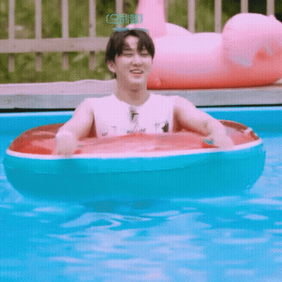 A Young Man Is Floating In A Swimming Pool With An Inflatable Raft . GIF