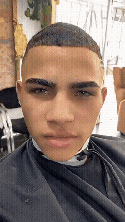 A Young Man Is Getting His Hair Cut By A Barber In A Salon . GIF