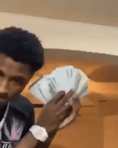 A Young Man Is Holding A Bunch Of Money In His Hands . GIF