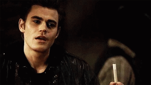 A Young Man Is Holding A Cigarette In His Hand And Smoking It . GIF