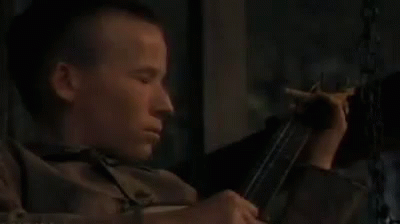 A Young Man Is Holding A Gun And Smoking A Cigarette . GIF